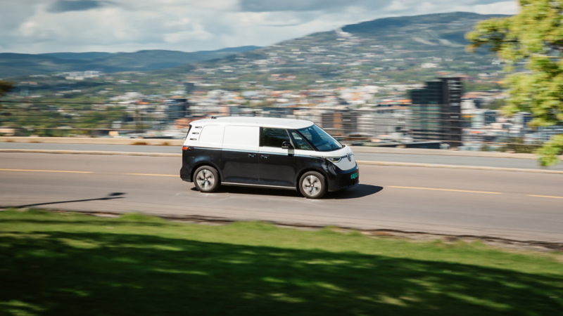 vw id buzz cargo varebil kjører nedover en vei, Oslo by ses i bakgrunnen