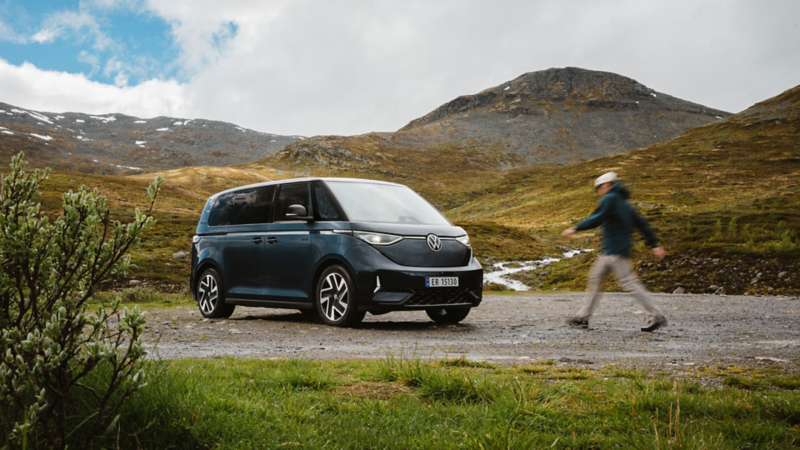 en person går mot vw id buzz familiebil i fjellet