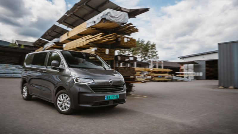 vw transporter varebil kjører forbi en stabel med ved