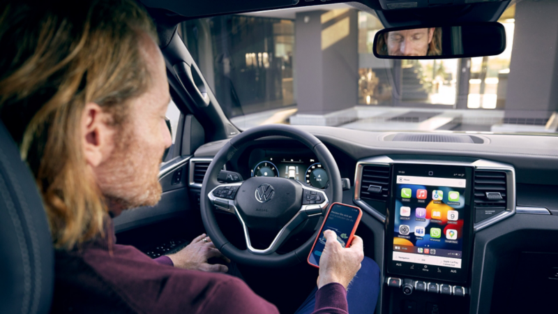 en person sitter i vw amarok pickup med telefonen i hånden