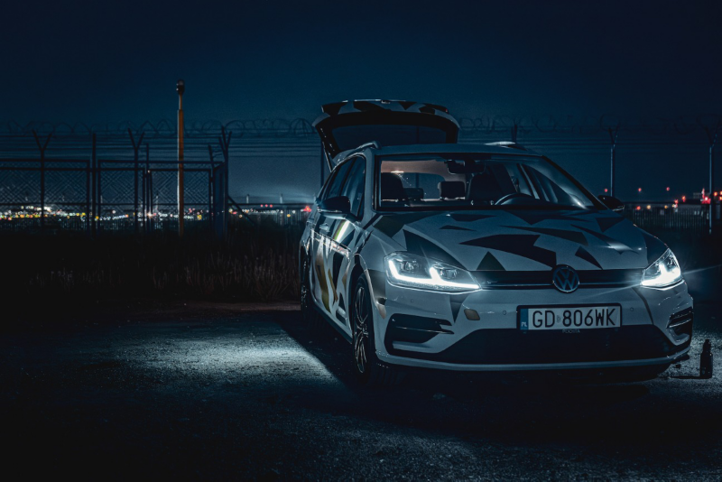 Biały Volkswagen na tle nocnego miasta.