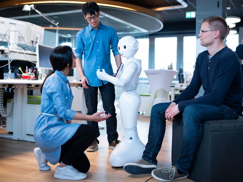 A woman and two men working on a humanoid robot