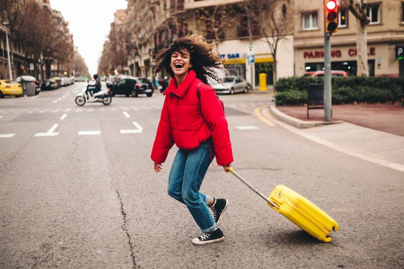 Eine Frau mit einem Koffer überquert die Straße