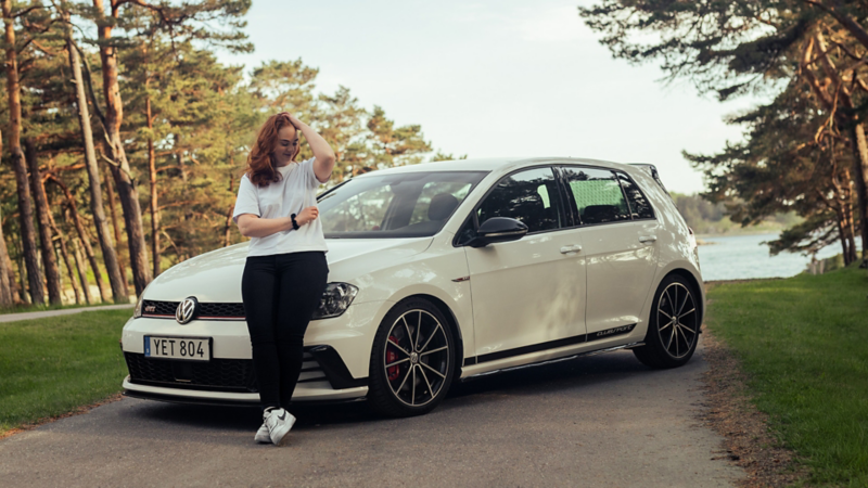 Emilia står framför sin vita VW Golf GTI