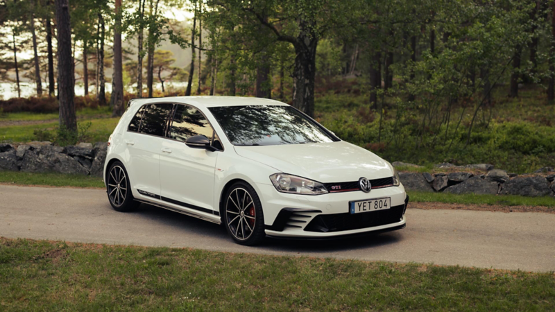 En vit Golf GTI står snett parkerad på en smal vgäg