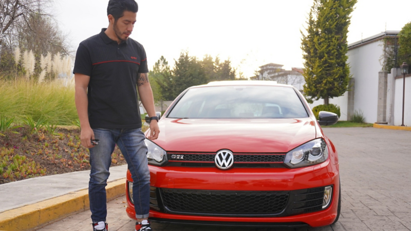 Alex frente a su Golf GTI rojo