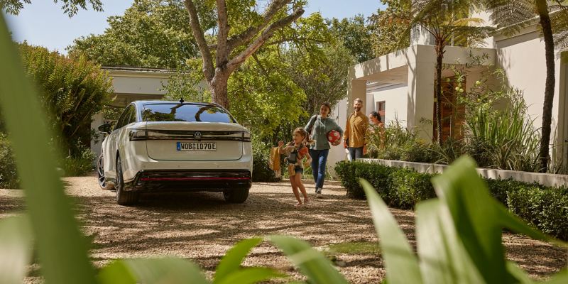 Eine glückliche Familie geht zu ihrem VW ID.7, um einen Ausflug zu machen