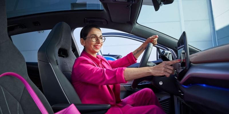 Μια γυναίκα κάθεται σε ένα ηλεκτρικό αυτοκίνητο Volkswagen και ενημερώνεται για τα ID. Software Updates