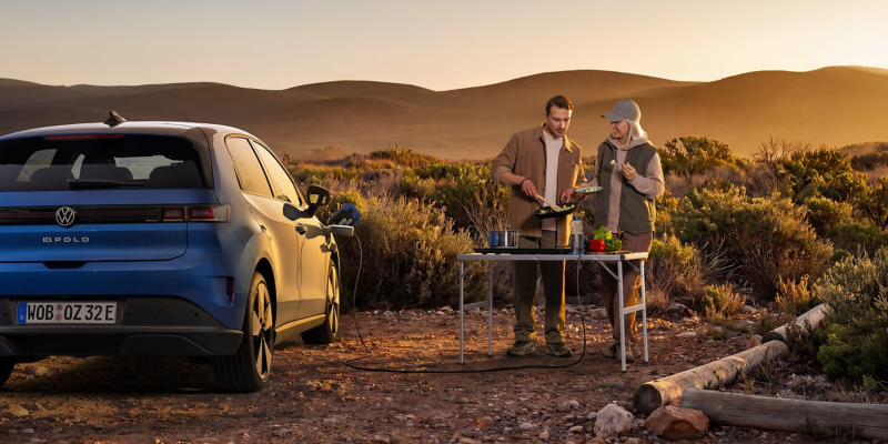 Dos personas cocinando al aire libre junto al ID. Polo con electricidad suministrada por el coche.