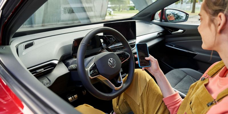 Kobieta siedzi w elektrycznym Volkswagenie i przeprowadza aktualizację Over-the-Air