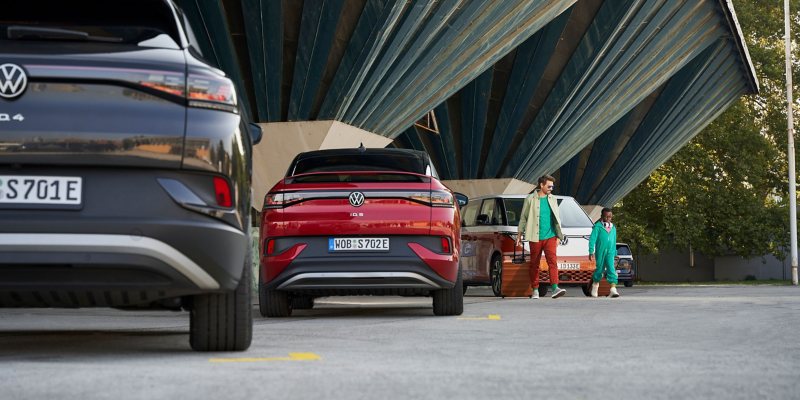 Zwei Menschen und drei ID. Modelle auf einem Parkplatz