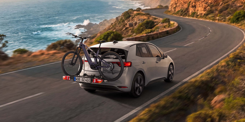 VW ID.3 Neo fährt Bergstraße entlang, auf dem VW Zubehör Fahrradträger ist ein E-Bike befestigt