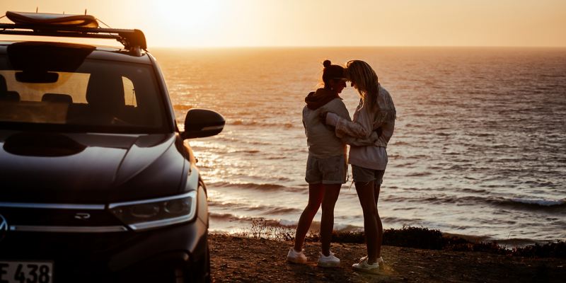 Zwei Frauen beim Sonnenuntergang am Meer mit ihrem VW T-Roc R