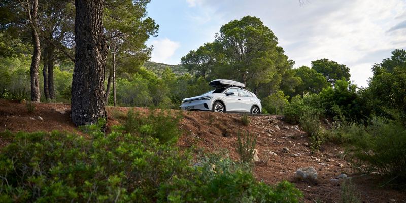 Een VW ID.4 met dakkoffer van VW-accessoires rijdt op een bergweg