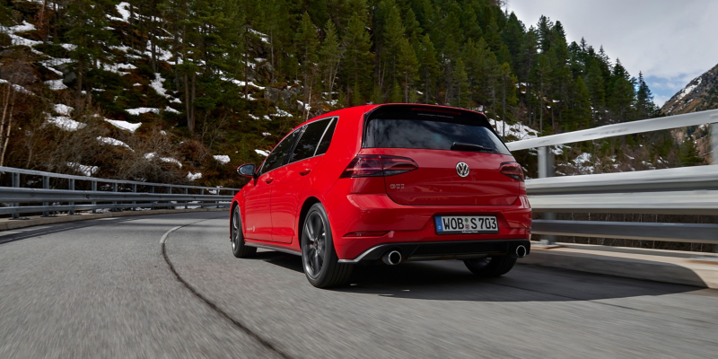 Roter VW Golf 8 GTI fährt um eine Kurve, vor ihm Berglandschaft