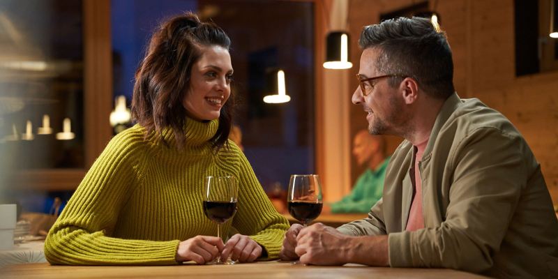 Eine Frau und ein Mann trinken gemütlich ein Glas Rotwein