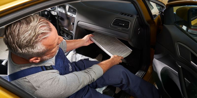 A VW service employee sits in a vehicle and replaces the filter