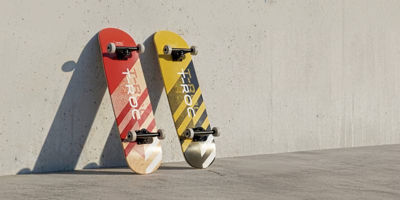 Δύο skateboards είναι ακουμπισμένα σε έναν τοίχο, το καθένα με την επιγραφή T-Roc στο κάτω μέρος.