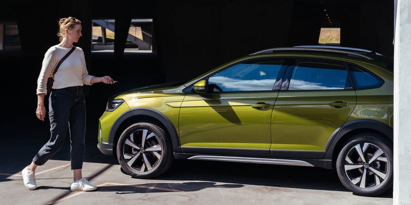 Een vrouw opent de centrale vergrendeling van een VW Taigo met de autosleutel