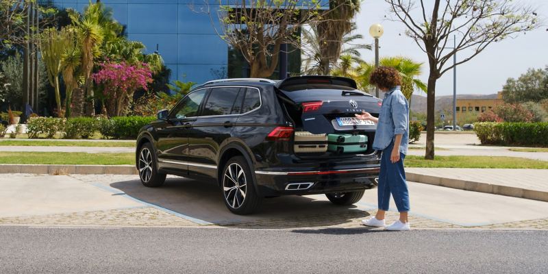 Une femme ferme le hayon du compartiment à bagages d’une VW Tiguan Allspace