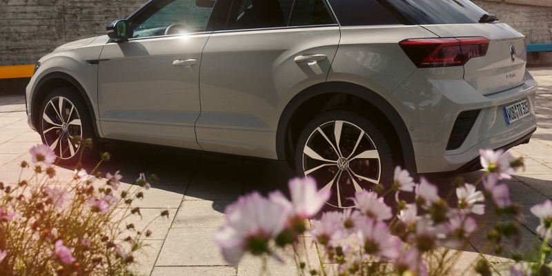 A white VW T-Roc stands in a yard with flowers
