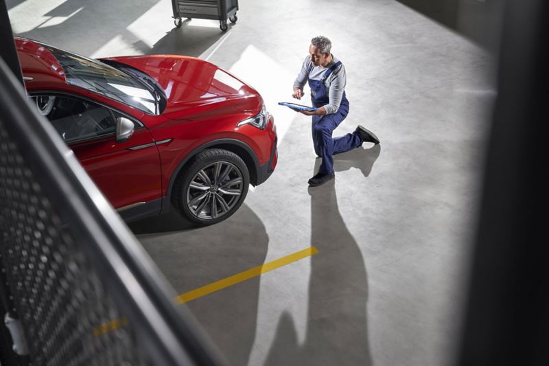 Un employé de VW services montre à sa cliente des pièces de carrosserie neuves ajoutées à sa voiture