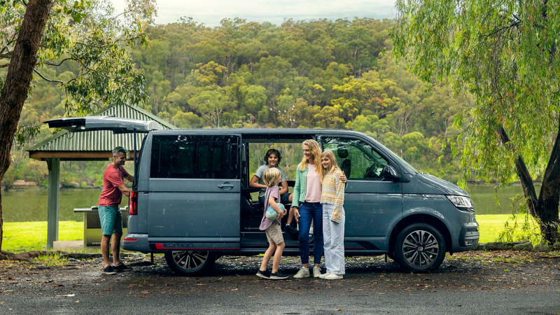 Family with the Volkswagen Multivan parked beside Lake.