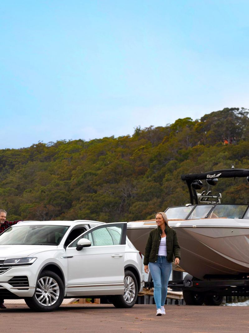 couple in front of a Touareg towing a boat