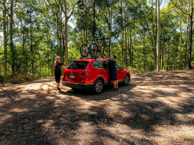 Couple parking red SUV VW car in the woods with cars on roof