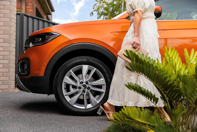 Woman walking in driveway next to orange VW with Alloy Wheels