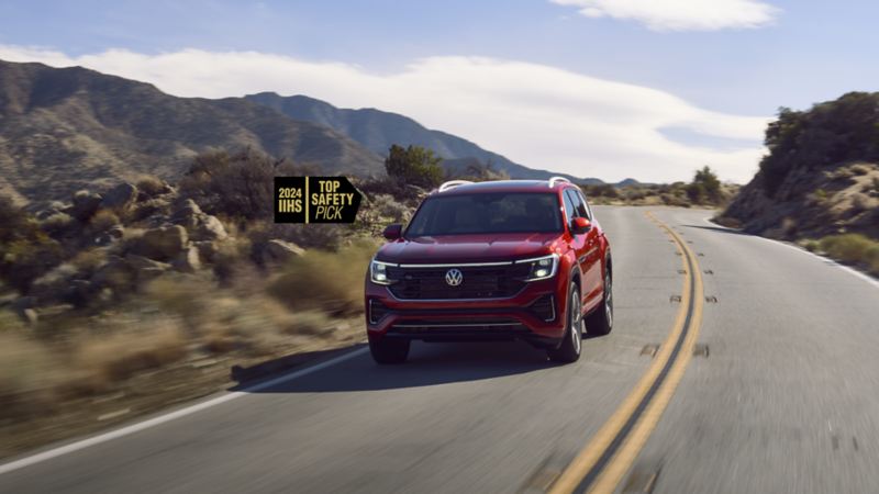 The 2024 Atlas, an IIHS "Top Safety Pick," is driving on a highway with a rocky landscape in the background.