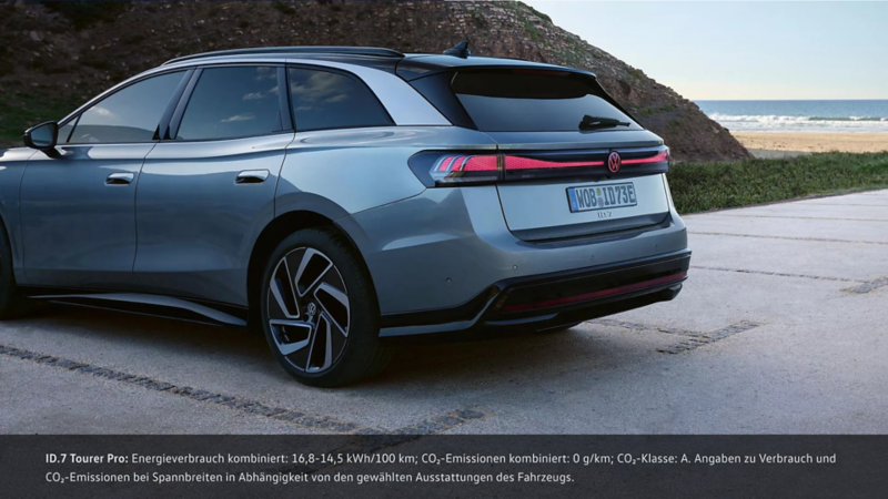 Grauer ID.7 Tourer steht auf einem Parkplatz am Strand, Heckansicht