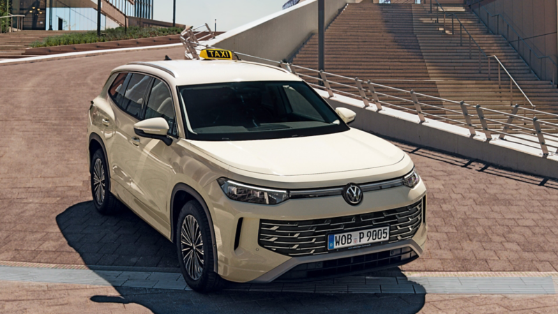 Der VW Tayron als Taxi steht in einer schönen Auffahrt. Auf dem Dach ein ‚TAXI‘-Schild
