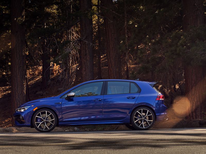 Blue Volkswagen Golf R parked next to a sun-lit pine forest., ink out to Vw’s owner’s manual.