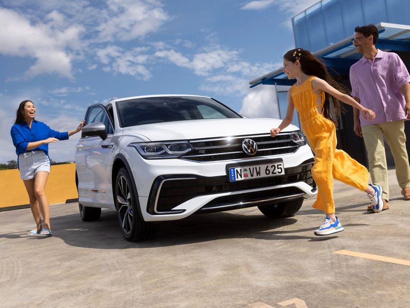 Family around Volkswagen Tiguan Allspace which is parked on the rooftop.