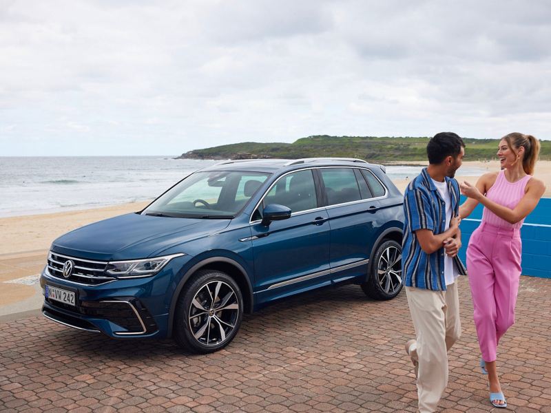 Side view of the Volkswagen Tiguan parked on the beach with couples around.