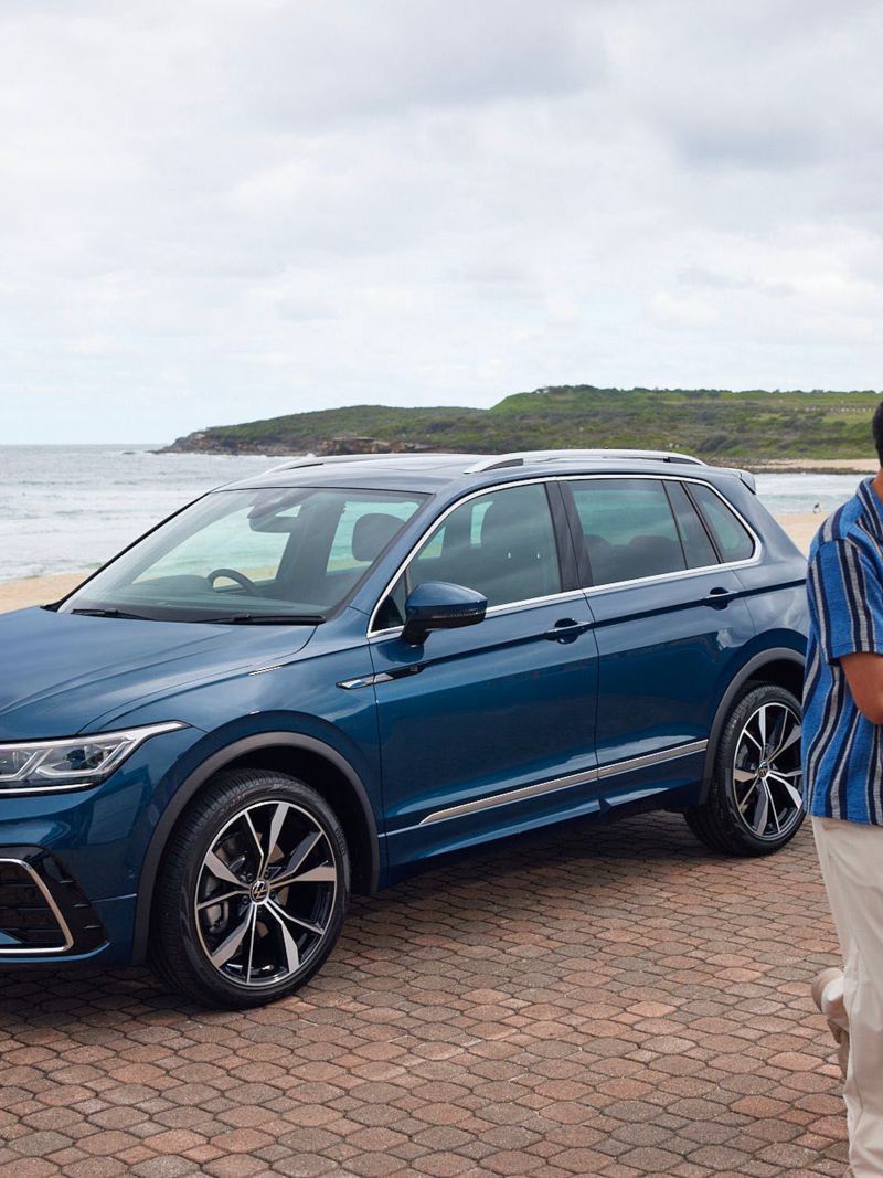 Side view of the Volkswagen Tiguan parked on the beach with couples around.