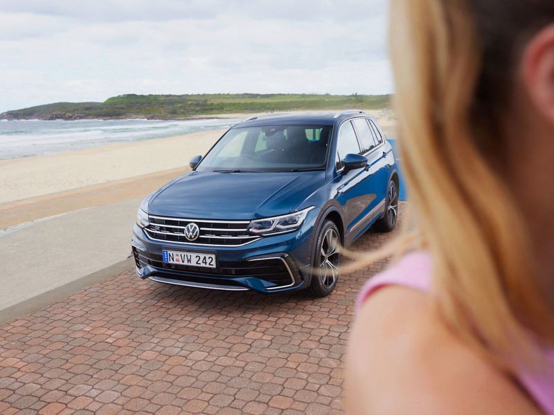 Woman in front with Volkswagen Tiguan in background.