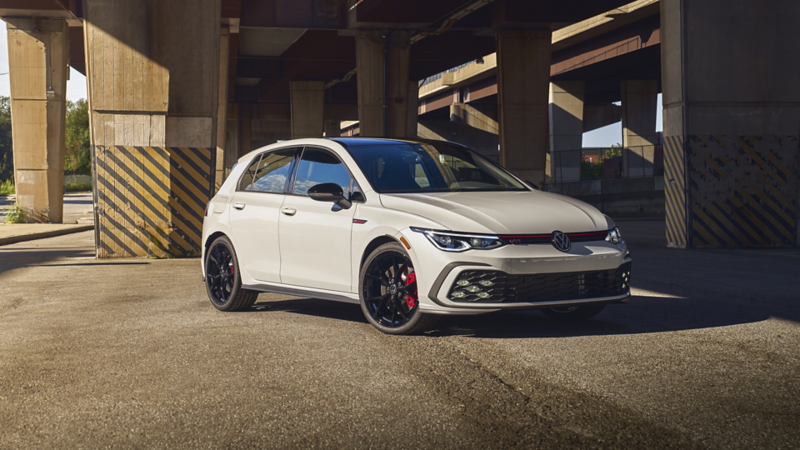 A white 2024 Golf GTI parked under a highway 