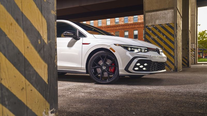 A woman is standing against a wall looking at the 2024 Golf GTI
