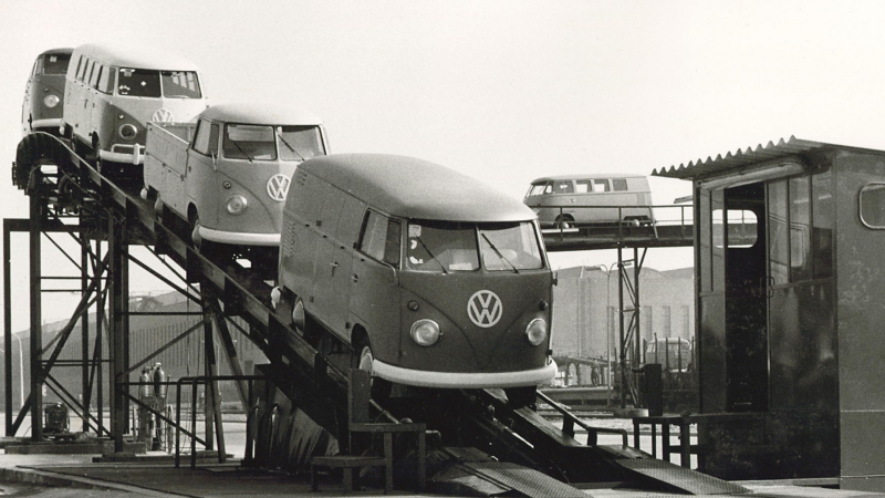 Historical photo showing vintage VW Transporters rolling off an assembly line.