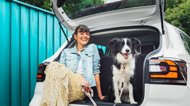 Woman sat in car boot with a dog next to her