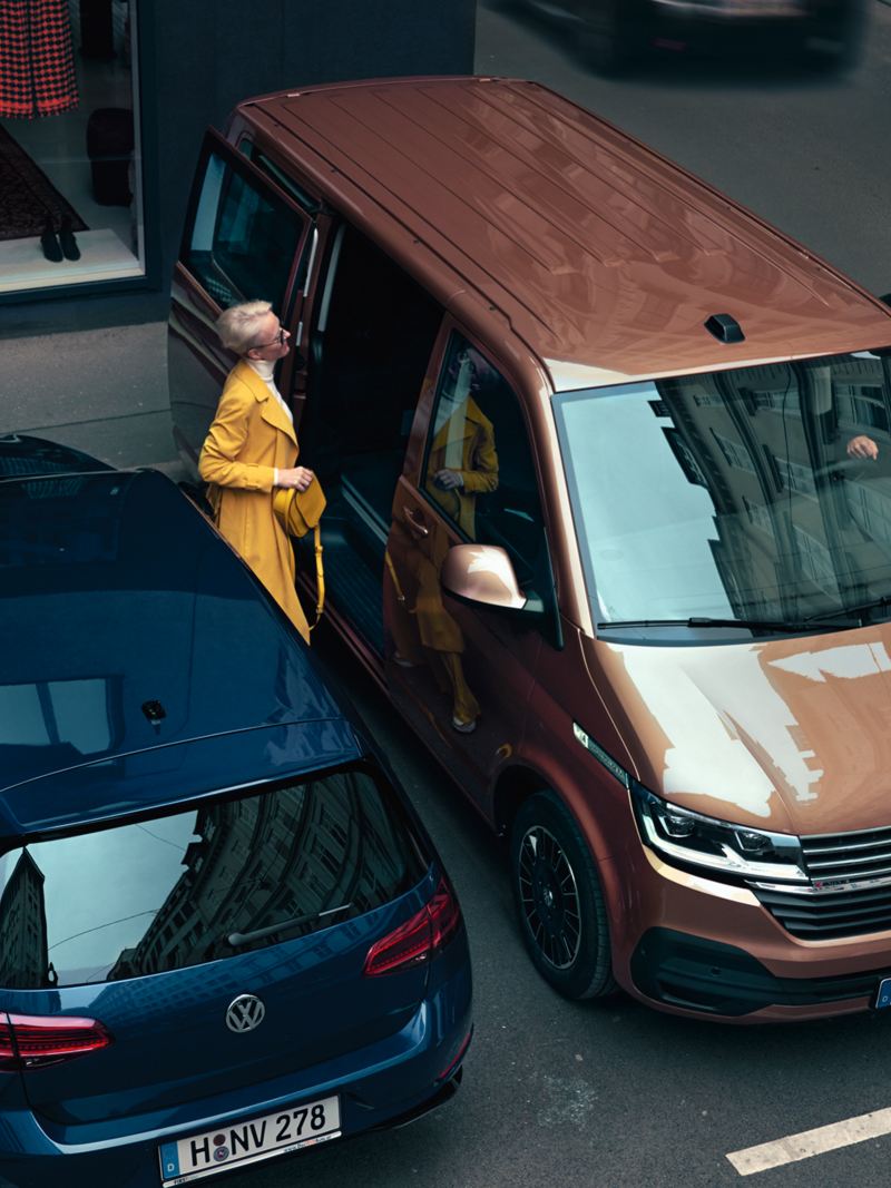 一位女性正準備上車，車款為古銅金的Multivan
