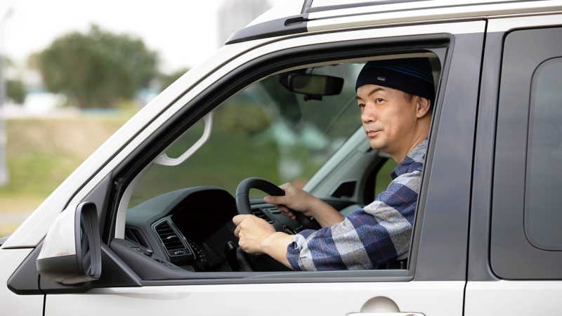 車主邱彥翔坐在California的駕駛座雙手握著方向盤，看向遠方