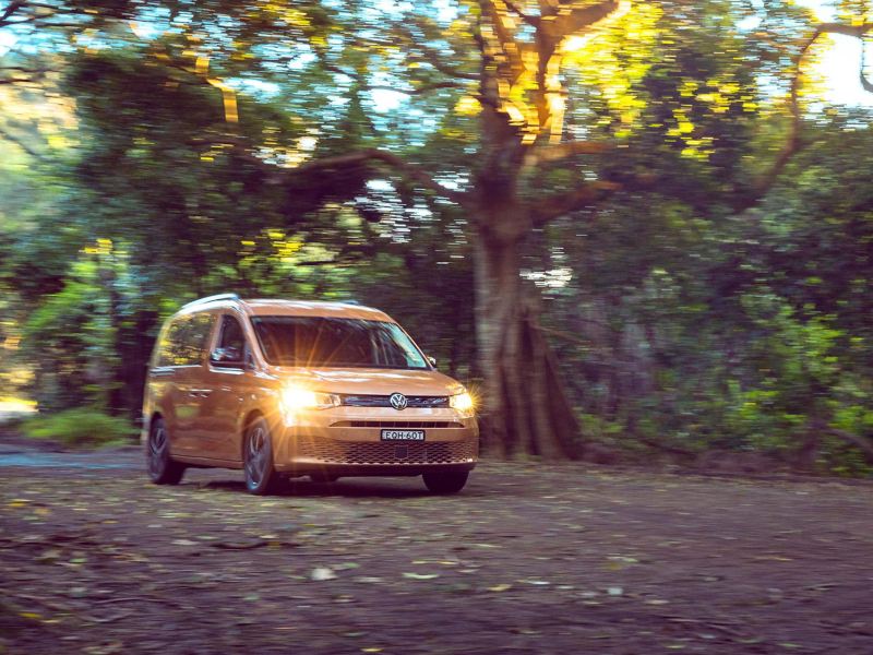 Volkswagen Caddy California driving on dirt road. 