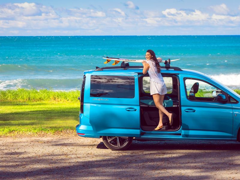 girl next to a surfboard on a rack.