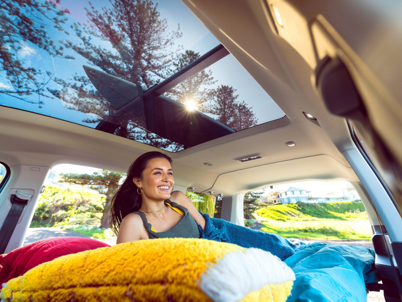 Woman relaxing inside Volkswagen Caddy California with doors open