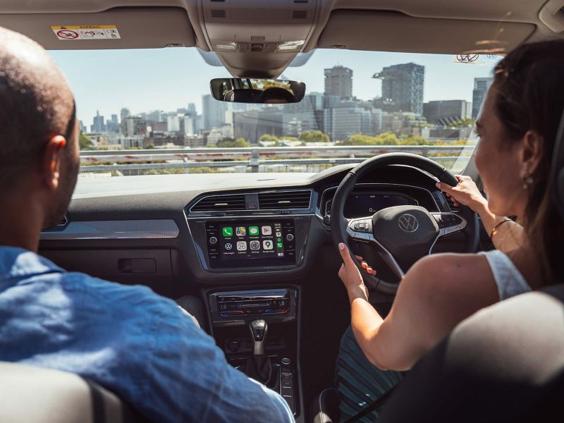 Looking over shoulder of female driver with hands on steering wheel of Volkswagen Tiguan.