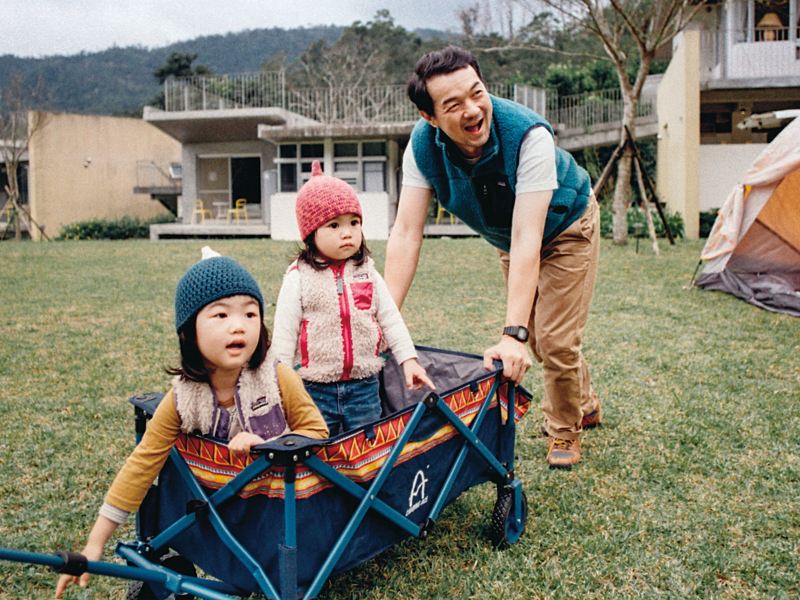 邱彥翔帶著兩個女兒坐在推車內，在草地上玩耍