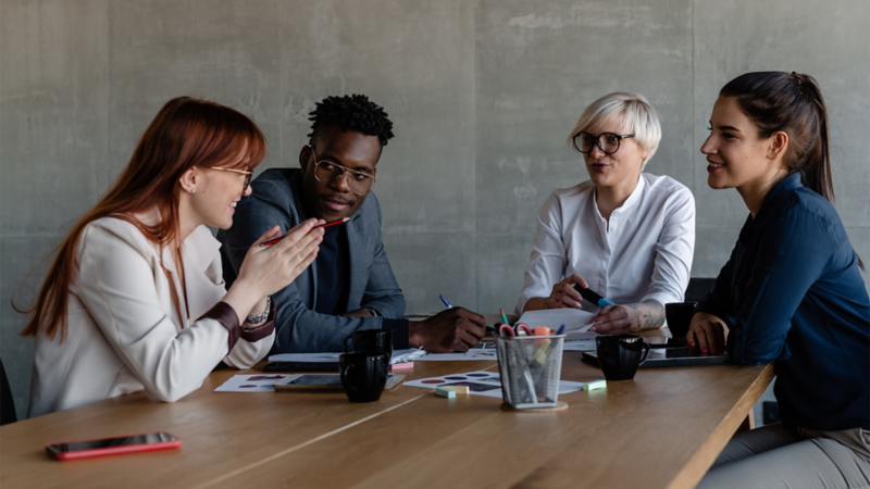 Four graduates in conversation at a table